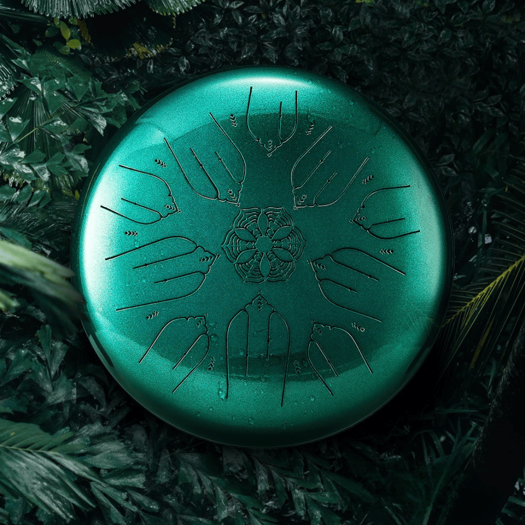 Hluru EQ Ethereal Tongue Drum in emerald green displayed outdoors among green leaves, highlighting its natural and healing aesthetic.