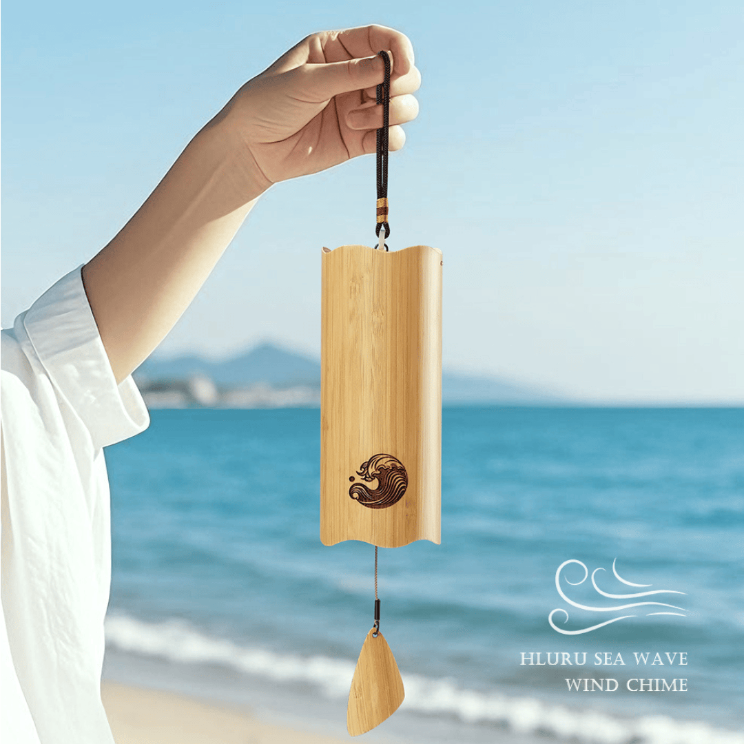 Hand holding a wooden wind chime with a beach in the background